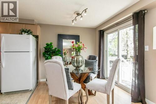 Dining area featuring wood-finish flooring, a glass-top table with a unique base, and access to an outdoor space via a sliding glass door - 71 Foxglove Crescent, Kitchener, ON - Indoor Photo Showing Dining Room