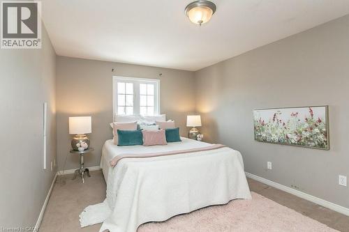 Carpeted bedroom with a window featuring white muntins, light beige walls, and a semi-flush ceiling light fixture - 71 Foxglove Crescent, Kitchener, ON - Indoor Photo Showing Bedroom