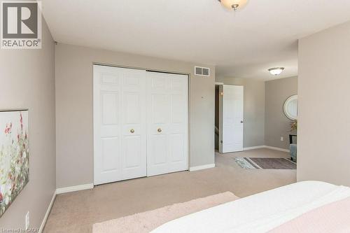 Spacious room featuring beige wall paint, white bi-fold closet doors with round brass hardware, and neutral carpet flooring - 71 Foxglove Crescent, Kitchener, ON - Indoor Photo Showing Bedroom