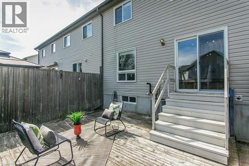 Rear wood-finish deck featuring sliding patio doors, a privacy fence, and an exterior wall light fixture - 71 Foxglove Crescent, Kitchener, ON - Outdoor With Deck Patio Veranda With Exterior