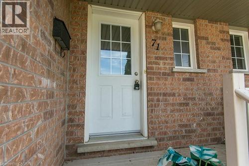 Brick exterior with a white paneled entry door, transom windows, exterior sconce lighting, and a wall-mounted mailbox - 71 Foxglove Crescent, Kitchener, ON - Outdoor With Exterior