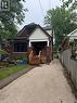 Brick exterior with white siding accents and a covered front porch featuring wooden steps - 21 Haddon Avenue S, Hamilton, ON 