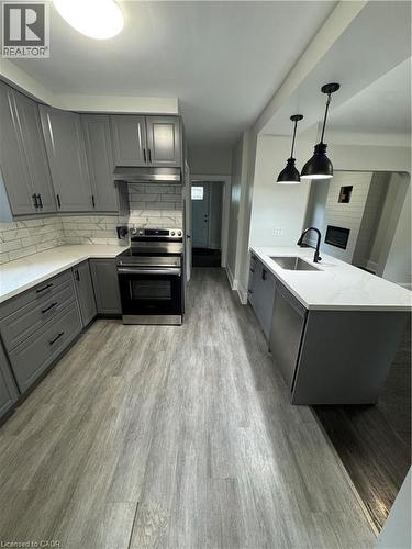 Modern kitchen featuring gray cabinetry with matte black hardware, stainless steel appliances, and white quartz countertops - 21 Haddon Avenue S, Hamilton, ON 