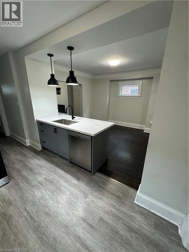 Kitchen island with grey cabinetry, undermount sink, and stainless steel dishwasher - 21 Haddon Avenue S, Hamilton, ON 