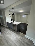 Kitchen island with grey cabinetry, undermount sink, and stainless steel dishwasher - 