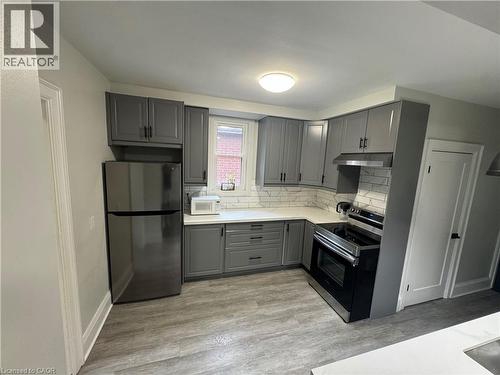 Modern kitchen featuring gray cabinetry with matte black hardware, stainless steel appliances, white countertops, and a white subway tile backsplash - 21 Haddon Avenue S, Hamilton, ON 