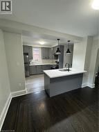 Modern kitchen featuring grey cabinetry, stainless steel appliances, and a central island with a sink - 
