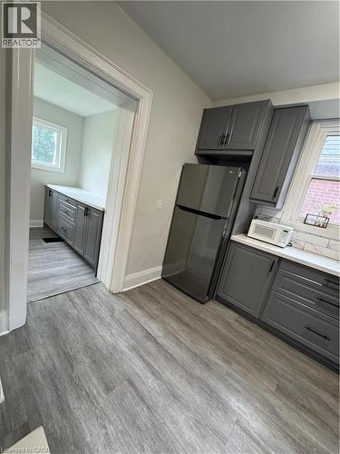 Kitchen featuring grey shaker-style cabinetry with matte black hardware, light-toned countertops, and a white subway tile backsplash - 21 Haddon Avenue S, Hamilton, ON 