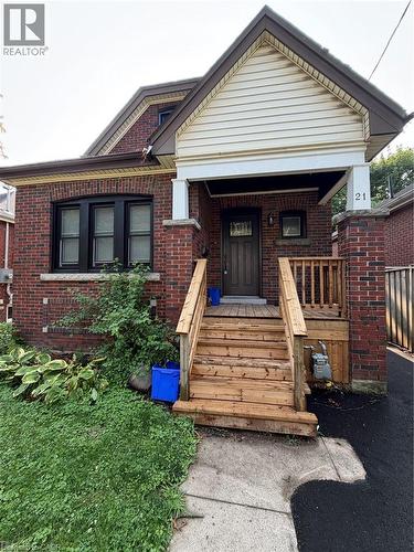 Brick exterior with a prominent front porch, wood steps, and a decorative front door - 21 Haddon Avenue S, Hamilton, ON - Outdoor