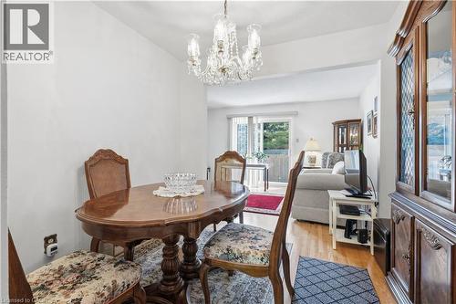 Formal dining area featuring a clear glass chandelier, wood-finish flooring, and a large display cabinet with glass doors - 1526 Westminster Place, Burlington, ON - Indoor Photo Showing Dining Room