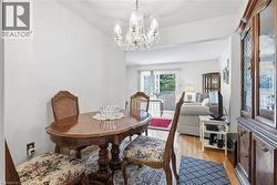 Formal dining area featuring a clear glass chandelier, wood-finish flooring, and a large display cabinet with glass doors - 