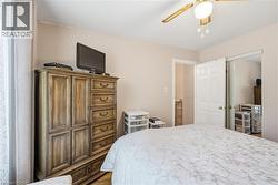 Bedroom featuring a ceiling fan with integrated lighting, wood-finish flooring, and a closet with bifold doors - 