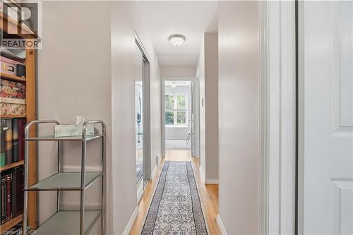 Hallway featuring wood-finish flooring, light neutral wall tones, a flush-mount ceiling light fixture, and a white paneled interior door - 1526 Westminster Place, Burlington, ON - Indoor Photo Showing Other Room