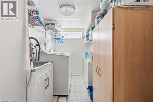 Dedicated utility space featuring a stainless steel utility sink, white base cabinetry with brushed nickel hardware, light wood-finish storage cabinetry, and a window for natural light - 1526 Westminster Place, Burlington, ON - Indoor Photo Showing Laundry Room