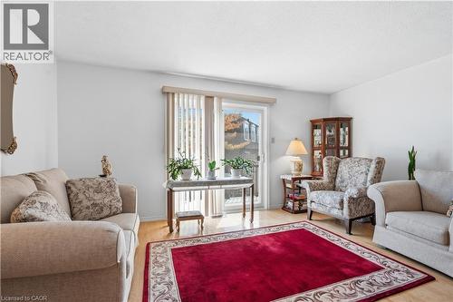 Bright living area featuring wood-finish flooring, white wall finishes, and a sliding glass door with vertical blinds - 1526 Westminster Place, Burlington, ON - Indoor Photo Showing Living Room