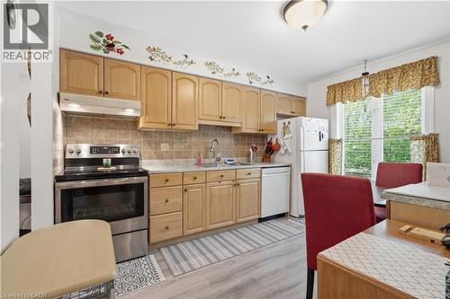 Kitchen featuring wood-finish cabinetry, tile backsplash, stainless steel range with overhead ventilation, and a double-basin sink - 1526 Westminster Place, Burlington, ON - Indoor Photo Showing Kitchen
