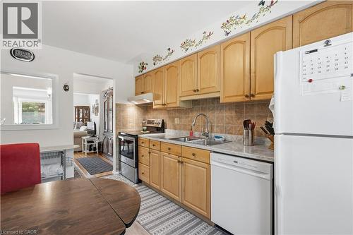 Kitchen featuring wood cabinetry, a tiled backsplash, and light-toned countertops - 1526 Westminster Place, Burlington, ON - Indoor Photo Showing Kitchen With Double Sink