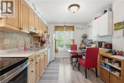 Kitchen featuring wood cabinetry, solid surface countertops, a tile backsplash, and wood-finish flooring - 1526 Westminster Place, Burlington, ON - Indoor Photo Showing Kitchen