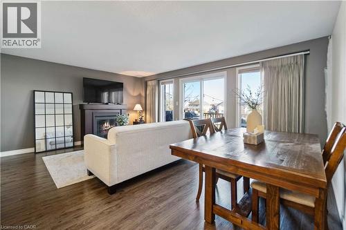 Open-concept living area featuring wood-finish flooring, a contemporary fireplace with a dark wood mantel, and expansive sliding glass doors - 27 Red Clover Crescent, Kitchener, ON - Indoor Photo Showing Living Room With Fireplace