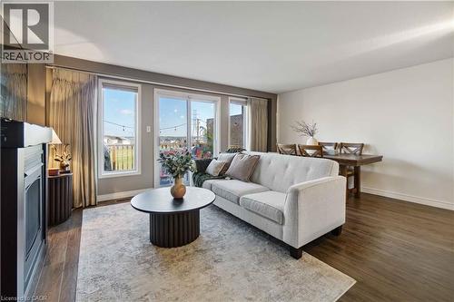 Open-concept living area featuring wood-finish flooring, a built-in electric fireplace, recessed lighting, expansive glass doors, and a large window - 27 Red Clover Crescent, Kitchener, ON - Indoor Photo Showing Living Room