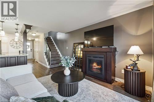 Spacious living area featuring wood-finish flooring and a staircase with dark wood treads and white risers - 27 Red Clover Crescent, Kitchener, ON - Indoor Photo Showing Living Room With Fireplace