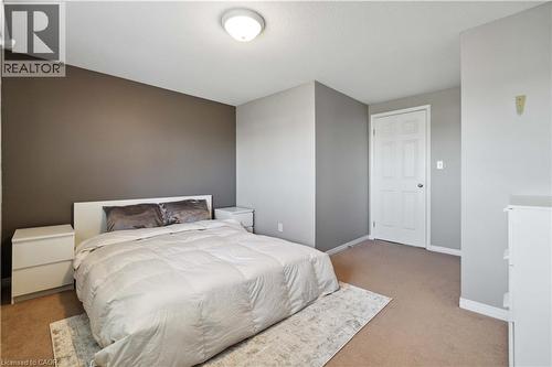 Spacious room featuring a neutral color palette, ceiling-mounted light fixture, and a paneled white door - 27 Red Clover Crescent, Kitchener, ON - Indoor Photo Showing Bedroom