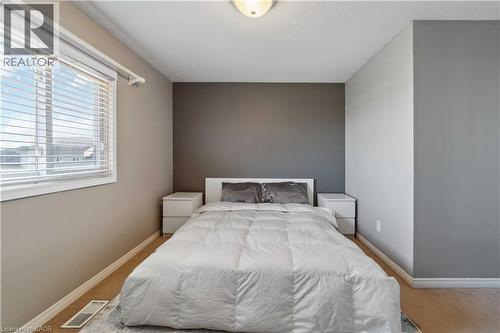 Bedroom featuring carpeting, a single window with blinds, a ceiling-mounted light fixture, and walls finished in a neutral palette with a distinct accent wall - 27 Red Clover Crescent, Kitchener, ON - Indoor Photo Showing Bedroom