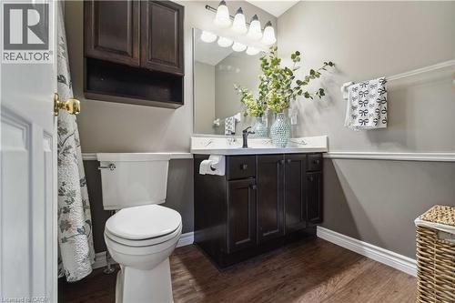 Bathroom featuring a dark wood-finish vanity with a light countertop, a wall-mounted mirror, and a four-light fixture - 27 Red Clover Crescent, Kitchener, ON - Indoor Photo Showing Bathroom