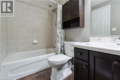Bathroom featuring a white bathtub with subway tile surround, dark wood-finish vanity with countertop, and wood-finish flooring - 27 Red Clover Crescent, Kitchener, ON - Indoor Photo Showing Bathroom