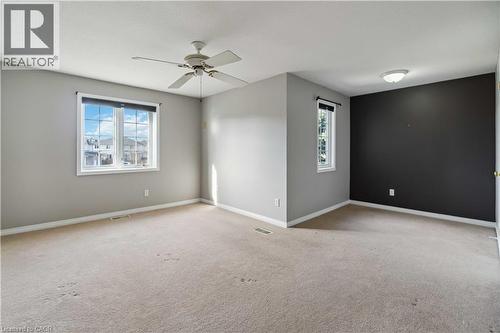 Spacious room featuring neutral carpet flooring, light gray painted walls, and a contrasting dark accent wall - 27 Red Clover Crescent, Kitchener, ON - Indoor Photo Showing Other Room