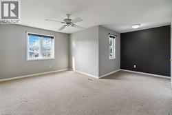 Spacious room featuring neutral carpet flooring, light gray painted walls, and a contrasting dark accent wall - 