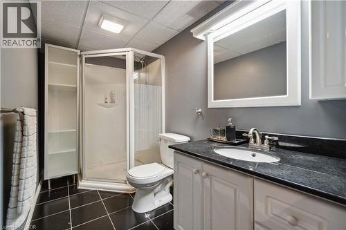 Bathroom featuring a black tile floor, white vanity with cabinet storage, dark countertop, and a corner shower enclosure - 27 Red Clover Crescent, Kitchener, ON - Indoor Photo Showing Bathroom