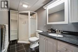 Bathroom featuring a black tile floor, white vanity with cabinet storage, dark countertop, and a corner shower enclosure - 