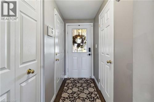 Entryway featuring a white paneled door with glass insert, wood-finish flooring, and multiple white paneled closet doors with brass hardware - 27 Red Clover Crescent, Kitchener, ON - Indoor Photo Showing Other Room