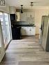 Kitchen featuring wood-finish flooring, white cabinetry, dark countertops, a tiled backsplash, and stainless steel appliances - 218 East 8Th Street, Hamilton, ON  - Indoor Photo Showing Kitchen 