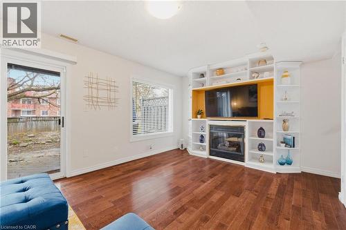 Wood-finish flooring throughout, featuring a built-in entertainment center with an integrated fireplace - 245 Bishop Street S Unit# 31, Cambridge, ON - Indoor Photo Showing Living Room With Fireplace