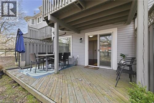Expansive wood-finish deck with a sliding glass door entry to the interior, featuring privacy fencing and an exterior wall light fixture - 245 Bishop Street S Unit# 31, Cambridge, ON - Outdoor With Deck Patio Veranda