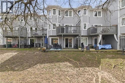 Rear exterior with light gray siding, multi-level decks with wooden railings, and ground-level patios - 245 Bishop Street S Unit# 31, Cambridge, ON - Outdoor