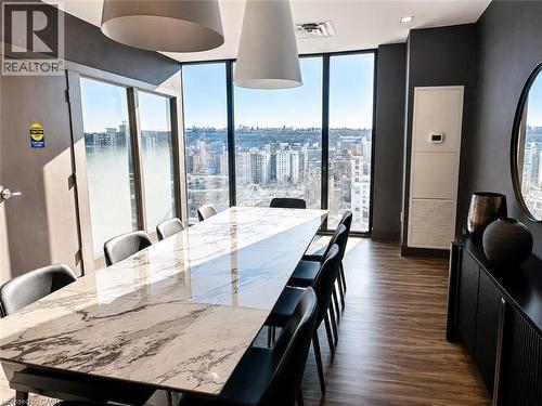 Spacious room featuring floor-to-ceiling windows, wood-finish flooring, and a large rectangular table with a patterned stone top - 75 James Street S Unit# 2614, Hamilton, ON - Indoor Photo Showing Dining Room