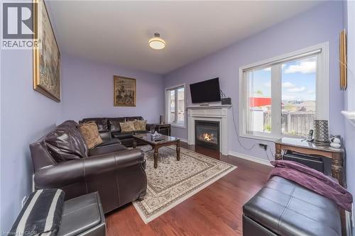 Living area featuring wood-finish flooring, a fireplace with a white mantel, and multiple windows for natural light - 675 Best Road, Milton, ON - Indoor Photo Showing Living Room With Fireplace