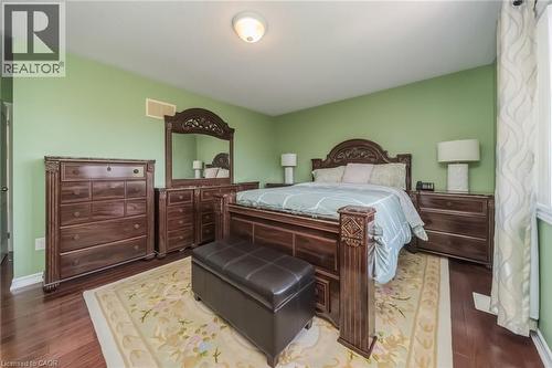 Spacious room featuring wood-finish flooring, light green walls, a single window with vertical drapery, and overhead lighting - 675 Best Road, Milton, ON - Indoor Photo Showing Bedroom