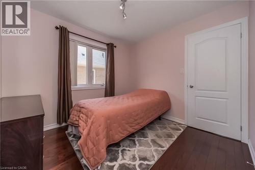Bedroom featuring wood-finish flooring, a double-hung window with drapery, a white interior door with paneling, and track lighting - 675 Best Road, Milton, ON - Indoor Photo Showing Bedroom
