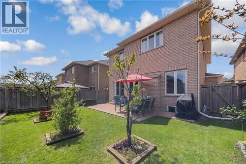 Expansive rear yard featuring a rectangular concrete patio, manicured lawn, and perimeter wood fencing - 675 Best Road, Milton, ON - Outdoor