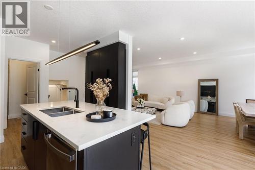 Kitchen island featuring a double-basin sink with a matte black faucet, integrated dishwasher, and a white countertop - 916 Steepleridge Court, Kitchener, ON - Indoor Photo Showing Other Room