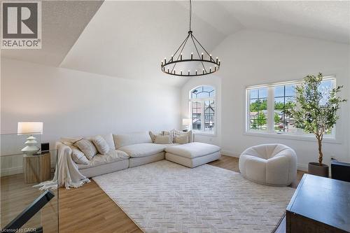 Vaulted ceiling with a contemporary chandelier, multiple windows, light wood-finish flooring, and a glass-paneled railing - 916 Steepleridge Court, Kitchener, ON - Indoor Photo Showing Living Room