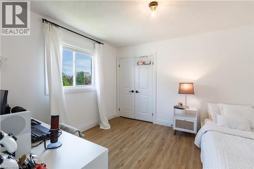 Bright room featuring wood-finish flooring, a double-panel door with black hardware, and a window with white trim and a black curtain rod - 916 Steepleridge Court, Kitchener, ON - Indoor