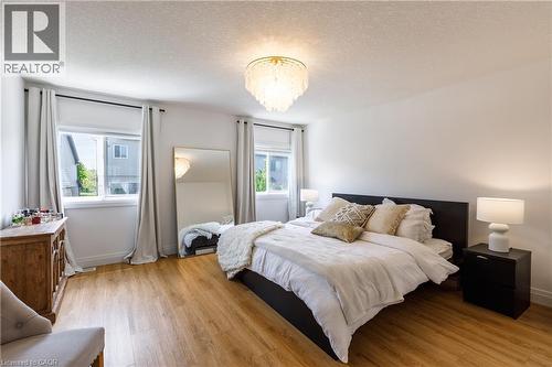 Bedroom featuring wood-finish flooring, white walls, and a crystal chandelier - 916 Steepleridge Court, Kitchener, ON - Indoor Photo Showing Bedroom