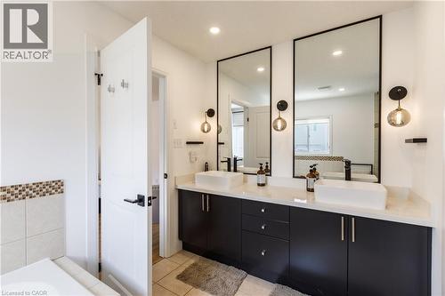 Double vanity featuring dark cabinetry, white countertops, and two vessel sinks with matte black faucets - 916 Steepleridge Court, Kitchener, ON - Indoor Photo Showing Bathroom