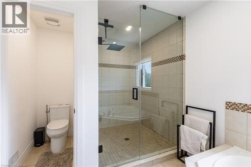 Glass-enclosed shower with tile surround and mosaic accent band, featuring a dark-finish rain shower head - 916 Steepleridge Court, Kitchener, ON - Indoor Photo Showing Bathroom