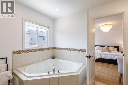 Corner jetted tub set within tiled surround with decorative mosaic accent - 916 Steepleridge Court, Kitchener, ON - Indoor Photo Showing Bathroom